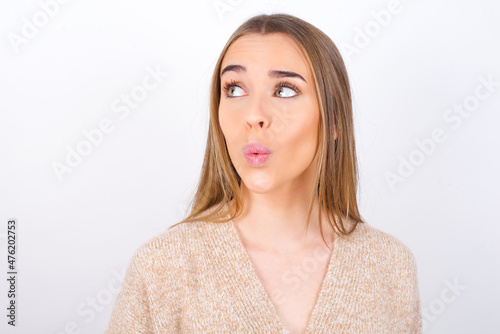 Shocked young caucasian girl wearing knitted sweater over white background look empty space with open mouth screaming: Oh My God! I can't believe this.