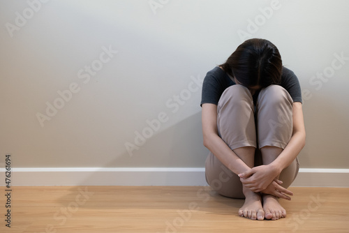 Depressed teenage sitting on the floor feeling sad.
