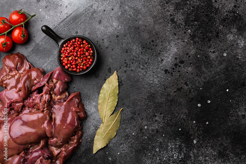 Raw liver chicken offal meat, on black dark stone table background, top view flat lay, with copy space for text