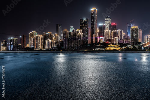 Panoramic skyline and modern commercial buildings with empty road. Asphalt road and cityscape at night.
