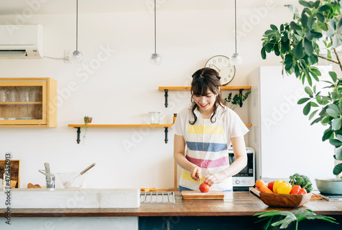 キッチンに立つ女性（野菜を切る） 
