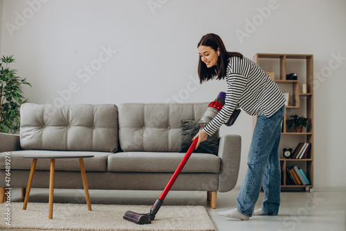 Woman doing house work with rechargeable vacuum cleaner