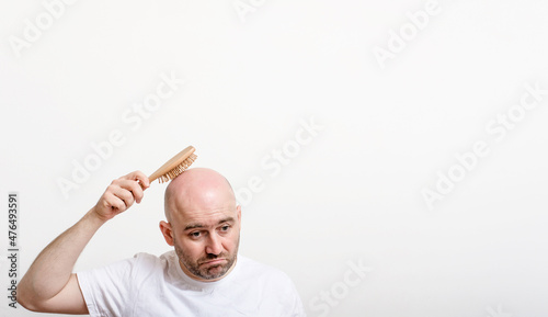 confused bald man with hair brush