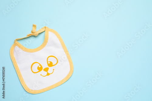 New baby bib on light blue background, top view. Space for text