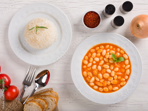 Turkish cusine food; Kuru fasulye and pilav ( navy beans and rice ) on the white table. Turkish traditional meal concept with top view.