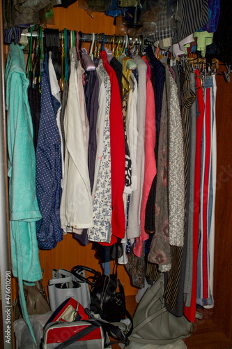 Lots of clothes on hangers, hanging in the closet. Wardrobe clutter. Sustainable life and smart consumption