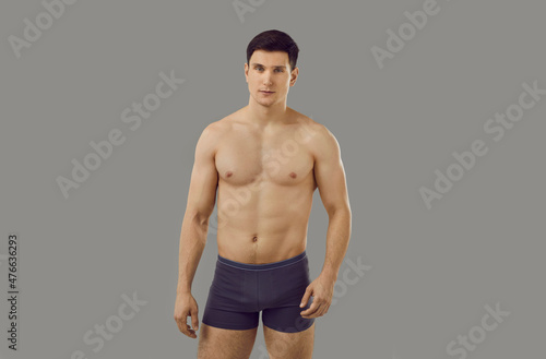 Portrait of muscular young Caucasian man in underwear pose on grey studio background advertise clothing. Toned sporty sexy male model in briefs for underclothing wear campaign. Sale, fashion concept.