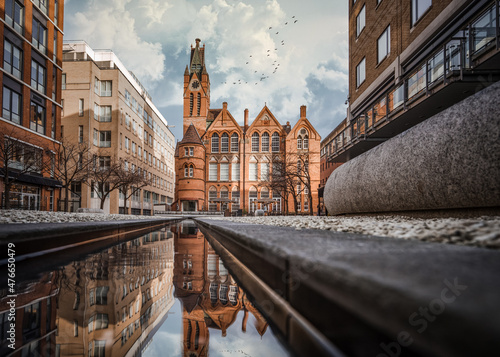 Brindley Place red brick church building reflected in water. West Midlands landmark buildings redevelopment in historic city centre reflection in stream. Birds and clouds in sky.