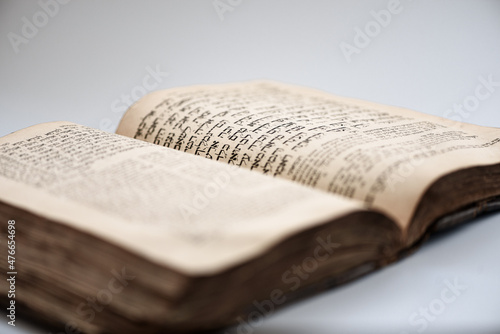 Worn shabby jewish book. Open page of Book of Genesis with blurred hebrew text. Closeup. Selective focus.