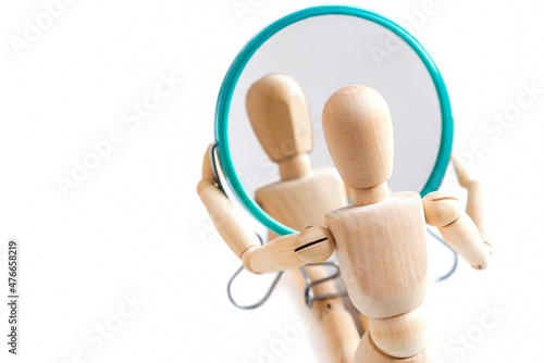 Wooden dummy looks at its reflection in the mirror