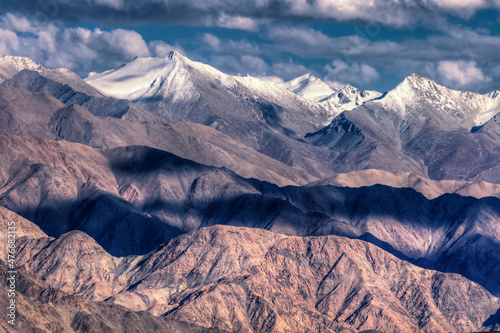 Rocky landscape of with ice peaks in background , blue sky with clouds, Ladakh, Jammu and Kashmir, India