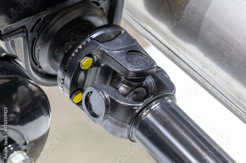 Closeup of a car cardan drive shaft with cardan cross joint and intermediate bearing support. Also known as universal joint, u-joint or cardan joint. Part of the transmission of a truck