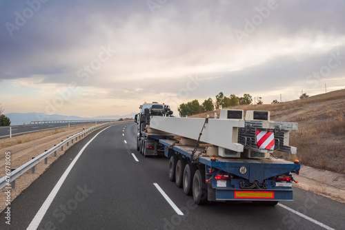 Special transport carrying columns circulating on a cloudy day.