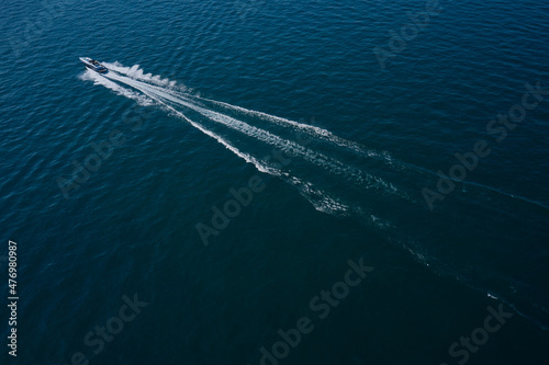 High-speed luxury boat diagonal movement on dark blue water. Boat performance fast movement on the water aerial view.