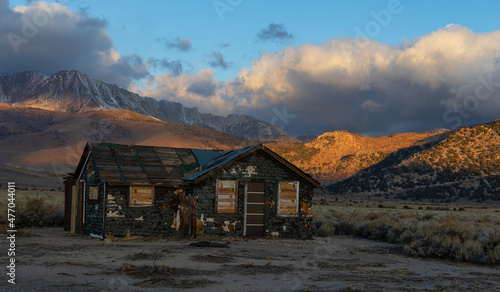 Abandoned old house at sunrise in front of the California Sierra Nevada mountains