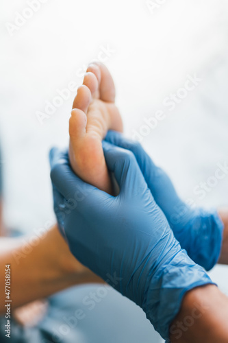 Close up of a podiatrist hands with medical gloves exploring the foot of a patient in the podiatry clinic.