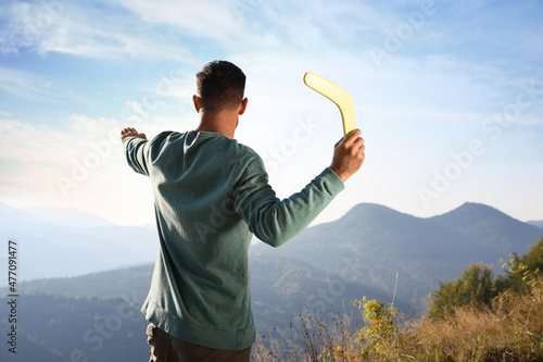Man throwing boomerang in mountains on sunny day, back view