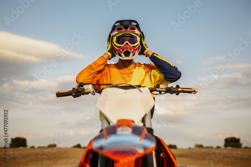 Portrait of motocross rider taking off helmet