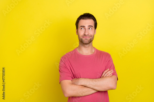 Photo of minded pensive interested guy crossed arms look empty space wear pink t-shirt isolated yellow color background