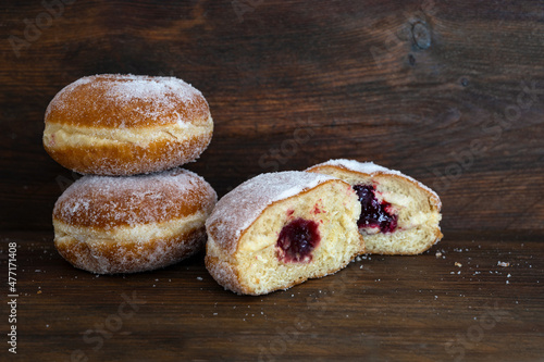 Berliner donuts or Krapfen filled with red jam, traditional sweet pastry for carnival and New Year, dark brown rustic wood, copy space, selected focus