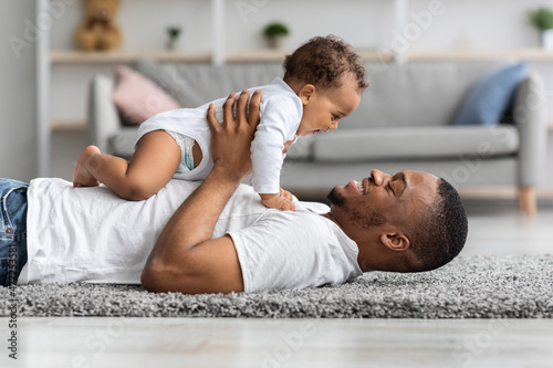 Father's Love. Happy Young Black Dad Bonding With Newborn Baby At Home