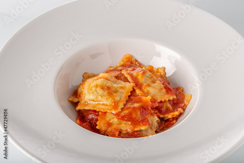 Ravioli pasta with tomato sauce in white plate, copy space