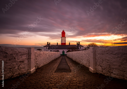 The pathway to the red and white striped, 23 meter tall, Souter Lighthouse in Marsden, South Shields as the sun rises