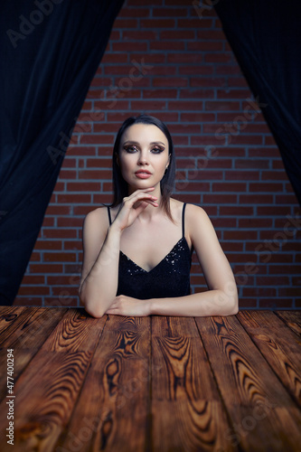 Portrait of a beautiful young brunette woman sitting at a wooden