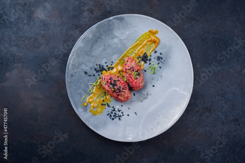 Modern style raw gourmet tartar from beef filet with Mustard sauce and capers served as top view on a design plate with copy space