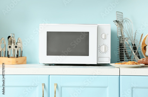 White microwave oven on counter near blue wall