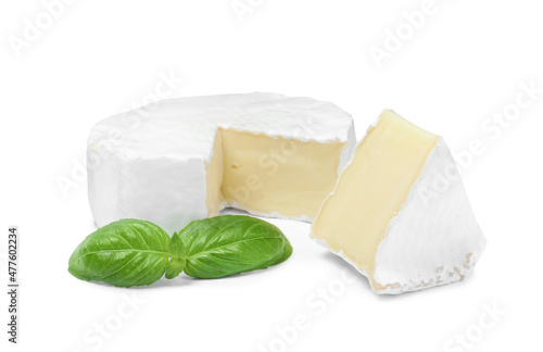 Tasty cut brie cheese with basil on white background