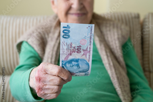 closeup wrinkled hands of old person holding money, Turkish lira banknotes