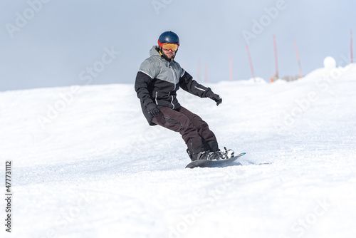 Young man snowboarding on the slopes of a ski resort.