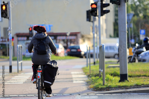 Kobieta na rowerze z plecakiem jedzie ścieżką rowerową w mieście, Wrocław. 