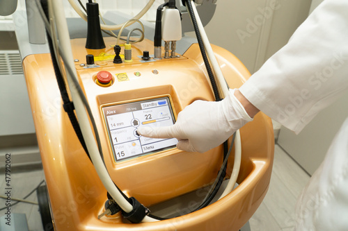 The hand of a beautician in a glove presses the monitor in a modern laser machine .Apparatus for laser hair removal. Epilation and spa concept.