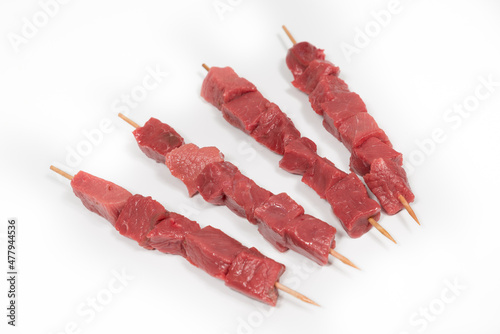 Four veal and beef skewers on a white background