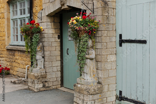 two stone ststues with hanging baskets of flowers above them