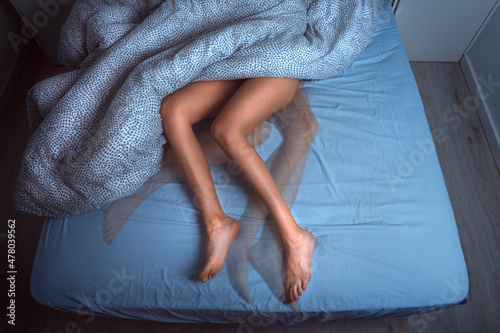 Woman sleeping in the bed and suffering from RLS or restless legs syndrome