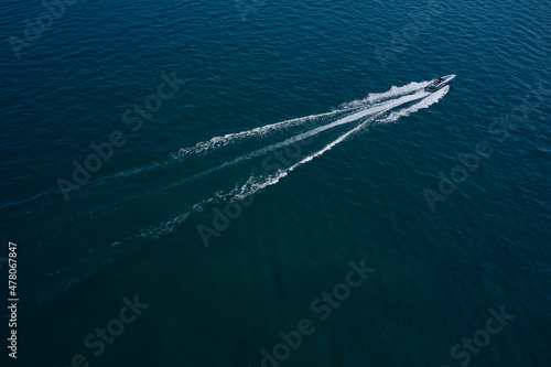 Boat performance fast movement on the water aerial view. High-speed luxury boat diagonal movement on dark blue water.