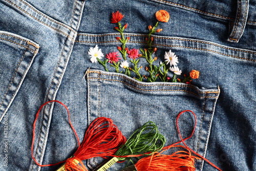 Creative DIY project, hand embroidery at home on jeans, creative hobby, clothes recycle, floral embroidery design, colorful threads, embroidery needle