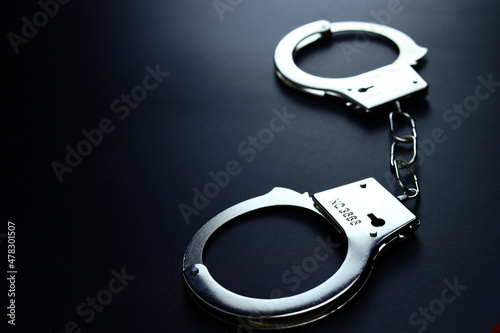 Police metal handcuffs on black background, close-up, selective focus