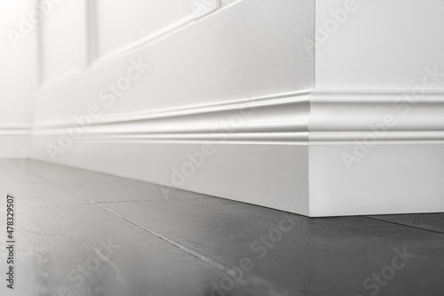 Close up of decorative, moulding white baseboard corner in empty room with copy space