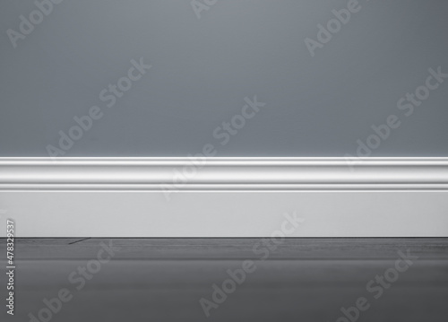 Close up of decorative, moulding white baseboard in empty room with copy space