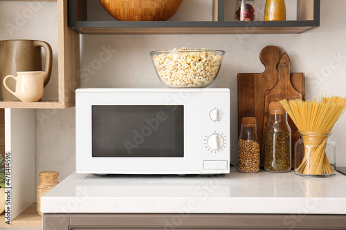 Modern microwave oven with bowl of popcorn on counter in kitchen