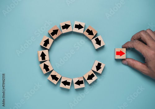 Disruption and technology transformation concept , Hand move out red arrow on wooden block cube move out from circle black arrow on blue background.