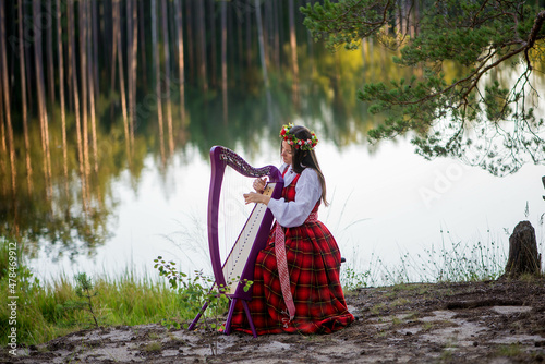 Young woman playing harp at the lake