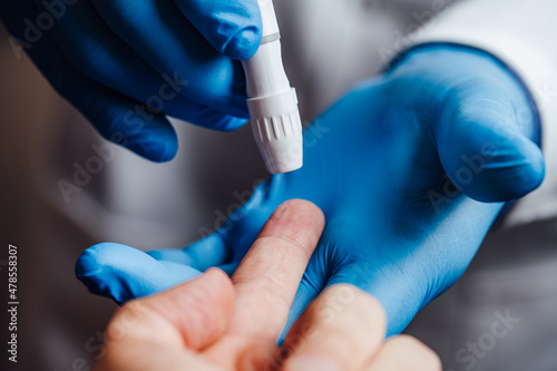 Doctor about to pierce a patient's finger with a lancet