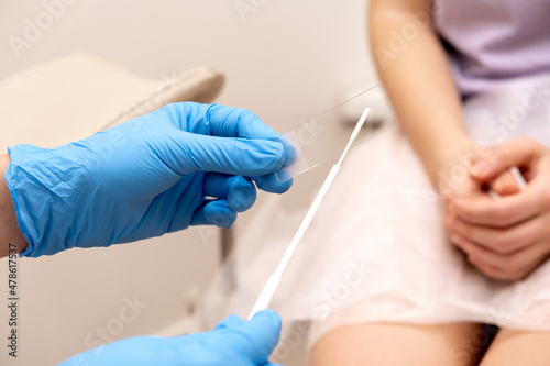 The gynecologist puts a smear on a slide glass for microscopy, hands close-up.Diagnosis of diseases of the genitourinary system.Women's health, medical concept.Selective focus.