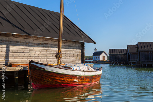 Old traditional wooden boathouses, an old sailing boat and Seafarer's Chapel at the Maritime Quarter in Mariehamn, Åland Islands, Finland, on a sunny day in the summer.