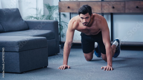 muscular sportsman doing press ups on floor at home